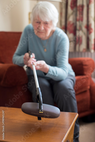 фотографія Senior Woman Using Reaching Arm To Pick Up Spectacles Case At Home