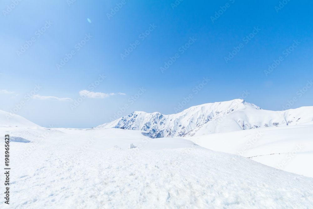 Tateyama Kurobe Alpine Route, the snow mountains wall with blue sky background in Toyama Prefecture, Japan.