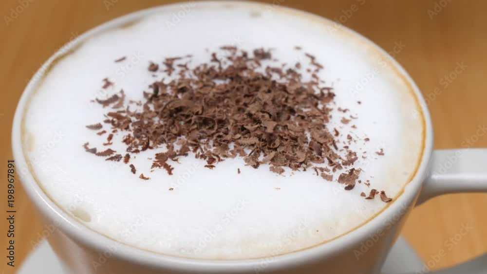 Milk froth in coffee cup sprinkled with dark chocolate, slow motion close up Milk froth in coffee cup sprinkled with dark chocolate, slow motion close up