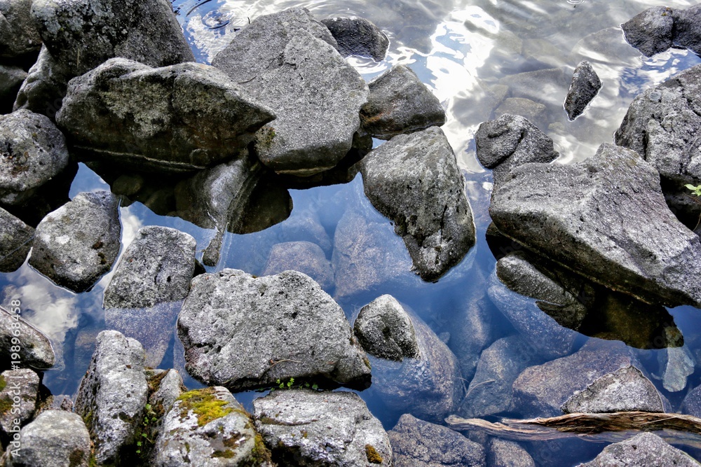 Stones and rocks on a transparent surface of lake where reflects mountain Tatras, Poland Stones and rocks on a transparent surface of lake where reflects mountain Tatras, Poland