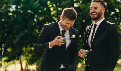 Groom and best man drinking at wedding party