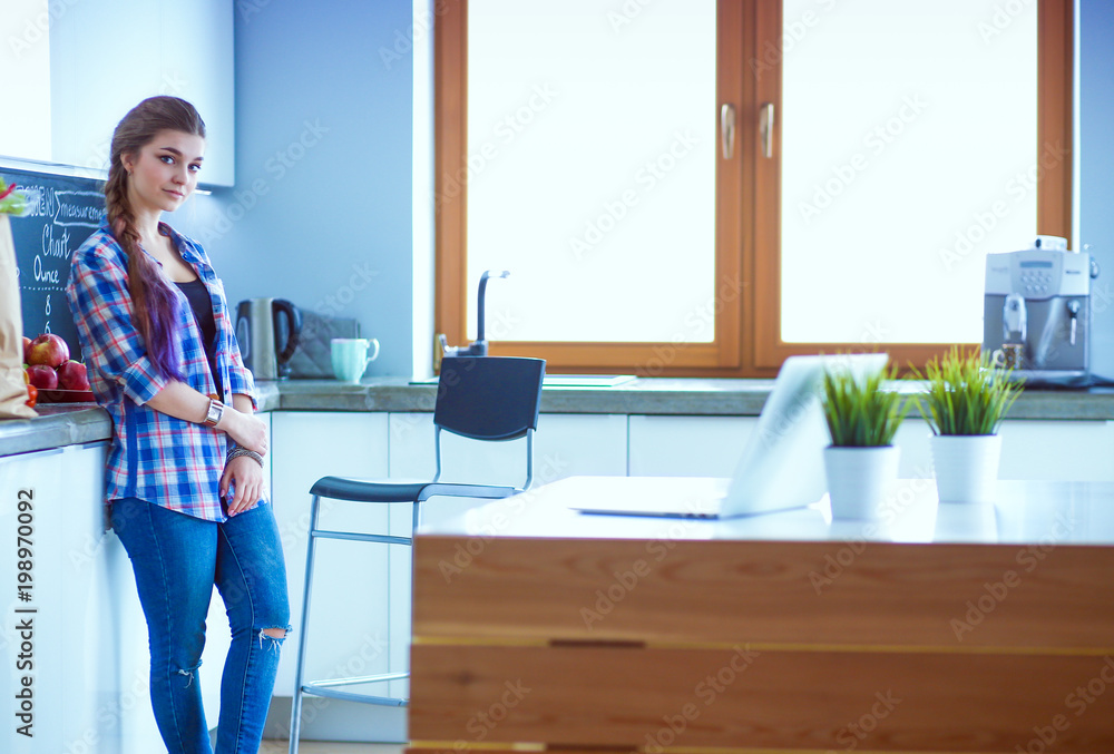 Portrait of young woman standing with arms crossed against kitchen background. Portrait of young woman standing with arms crossed against kitchen background.