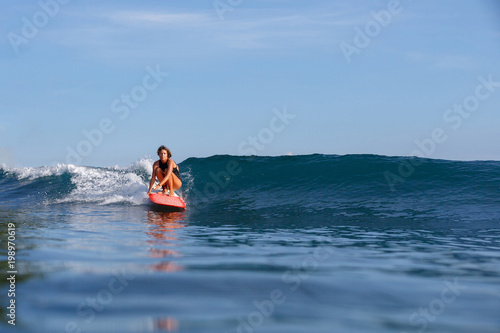 young female surfer riding wave on surfboard © LIGHTFIELD STUDIOS