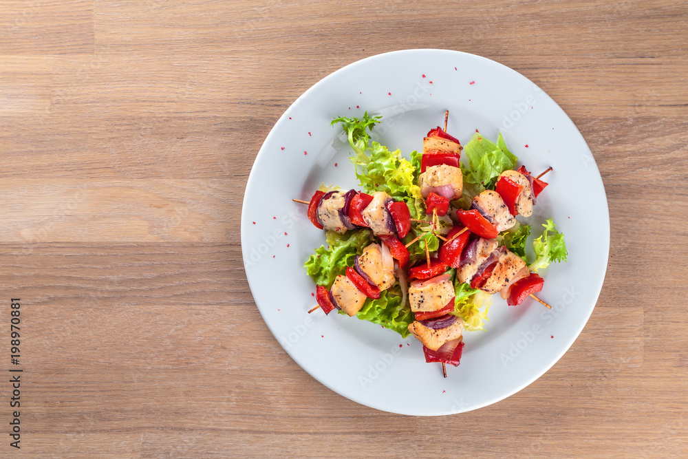 chicken fillet kebabs with roasted peppers, onions and lettuce on wooden skewers are on the plate chicken fillet kebabs with roasted peppers, onions and lettuce on wooden skewers are on the plate