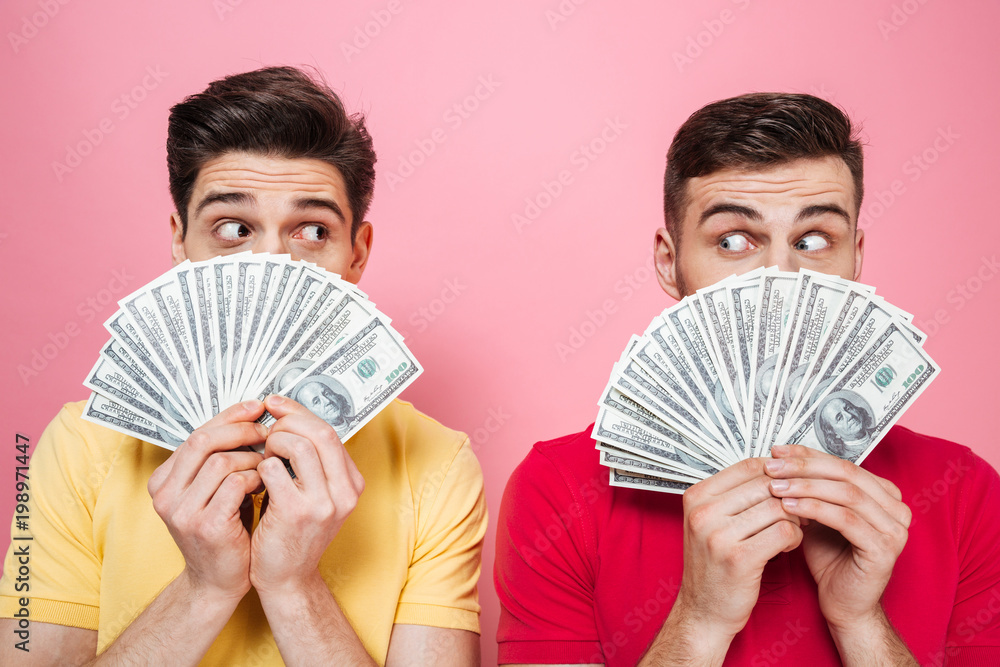 Portrait of a surprised gay male couple holding money Portrait of a surprised gay male couple holding money
