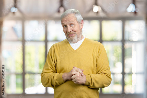 Portrait of surprised grandfather. Blurred checkered windows background.