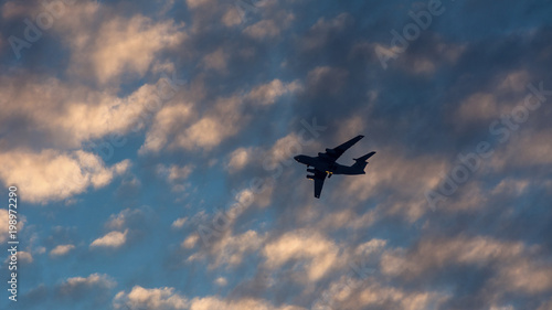 Silhouette of the plane in the clouds at sunset