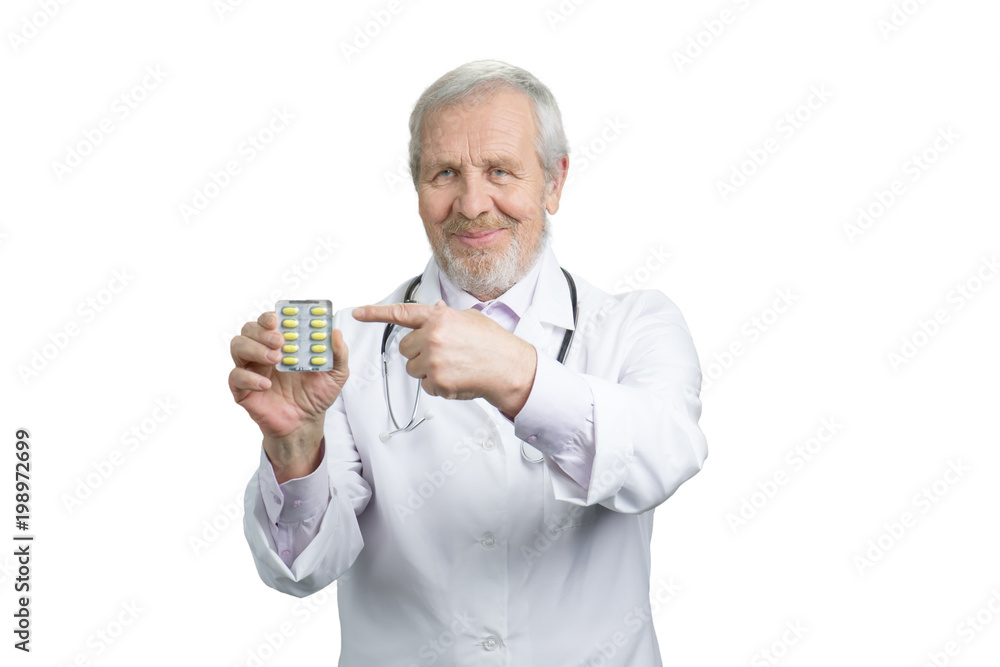 Senior doctor advertising pack of pills. Pointing and the medicine in capsules. White isolated background. Senior doctor advertising pack of pills. Pointing and the medicine in capsules. White isolated background.