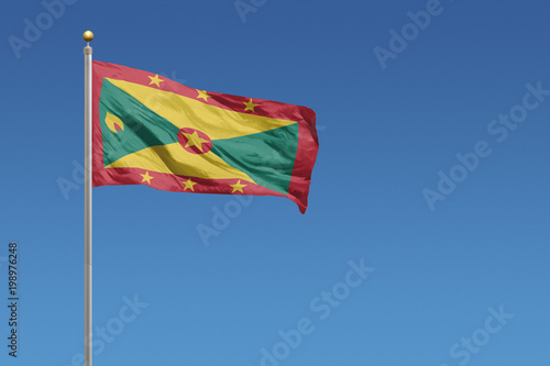 Flag of Grenada in front of a clear blue sky