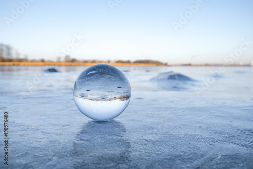 Transparent glass orb on a frozen lake with ice