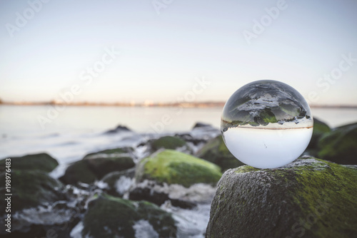 Glass orb on rocks by the sea