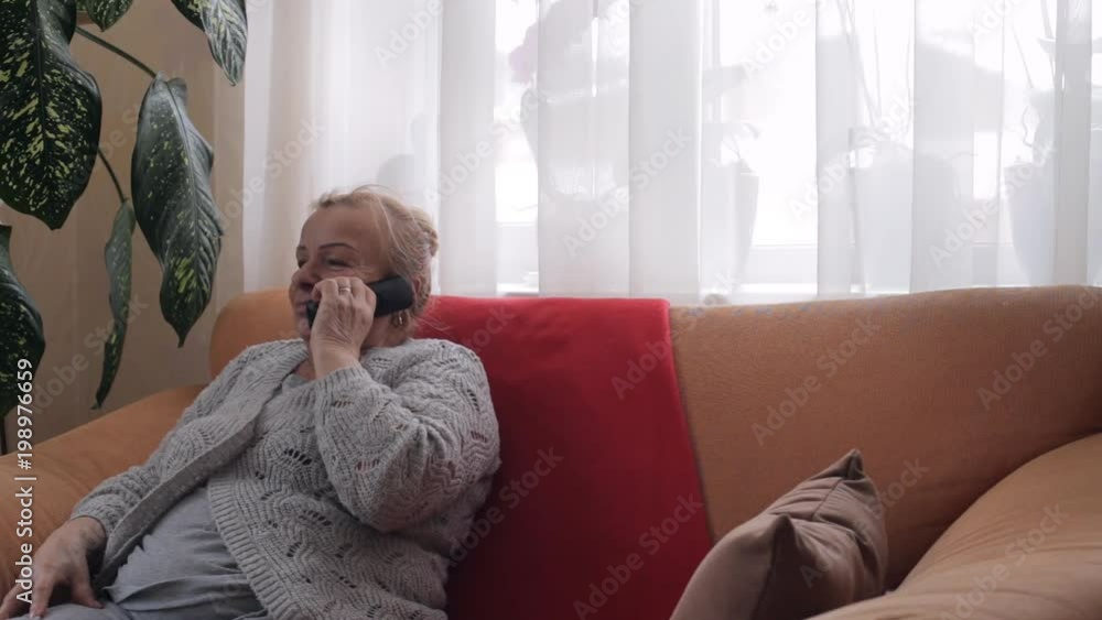 Old grandmother talking on phone sitiing on sofa Old grandmother talking on phone sitiing on sofa