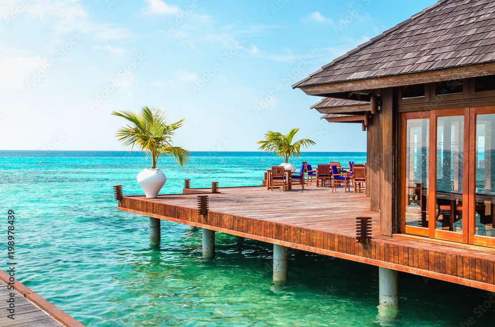 A wooden restaurant on the water against the backdrop of the azure waters of the Indian Ocean, Maldives
