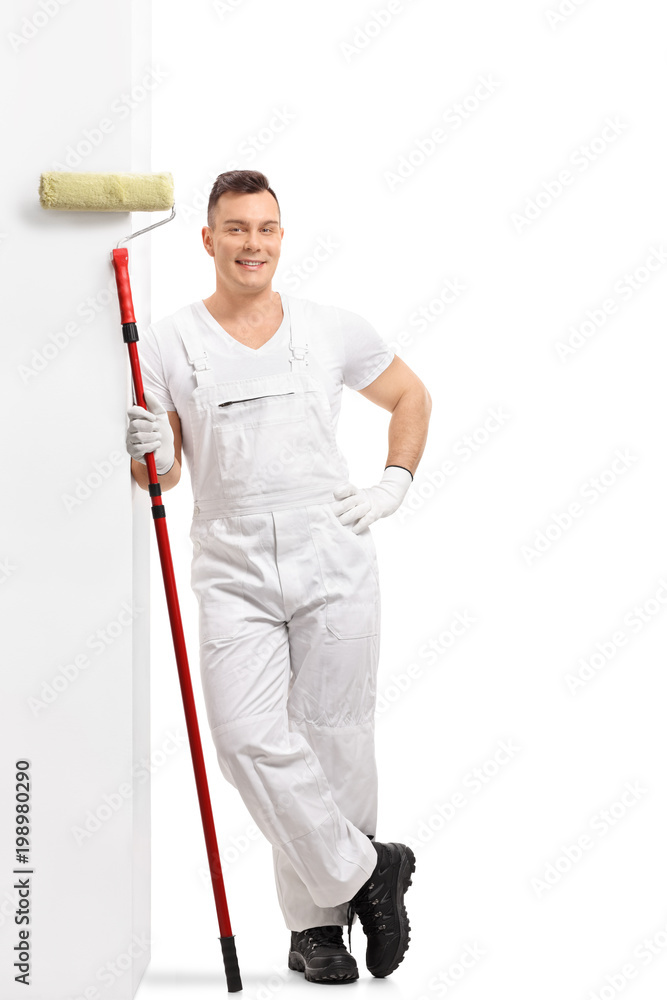 Painter with a paint roller leaning against a wall Painter with a paint roller leaning against a wall