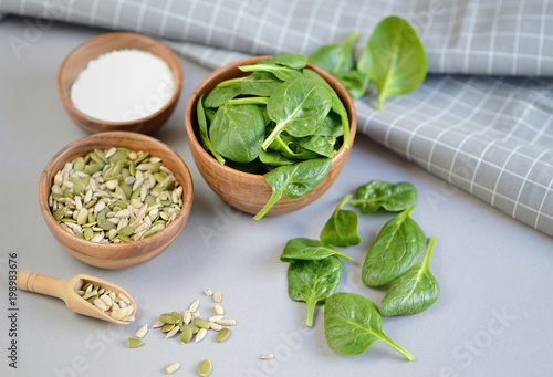 Fresh Spinach Leaves, Sea Salt and Seeds Nuts Mix in Wooden Bowl on Grey Background Healthy Food Concept Salad Ingredient 