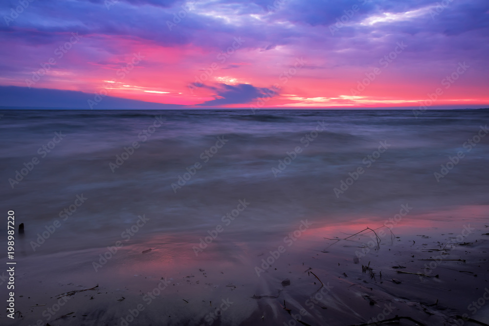 Beautiful twilight landscape. A long exposure of a sunrise or sunset and soft waves washing up the beach.