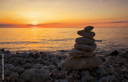 Pyramid of the small pebbles on the beach. Stones  against the background of the sea shore during sunset