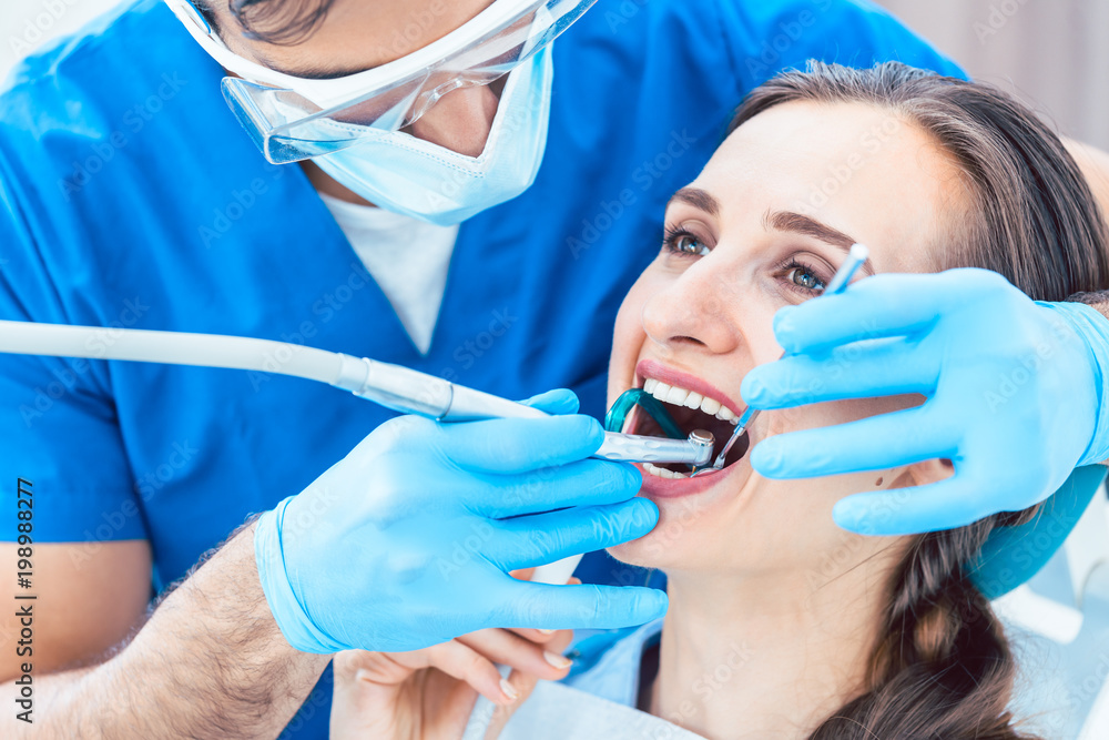 Side view close-up of a relaxed young woman during painless oral treatment in the modern dental office of an experienced and dedicated dentist Side view close-up of a relaxed young woman during painless oral treatment in the modern dental office of an experienced and dedicated dentist