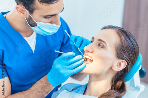 Young and beautiful woman looking with confidence at her reliable dentist during safe and painless dental treatment in a modern clinic
