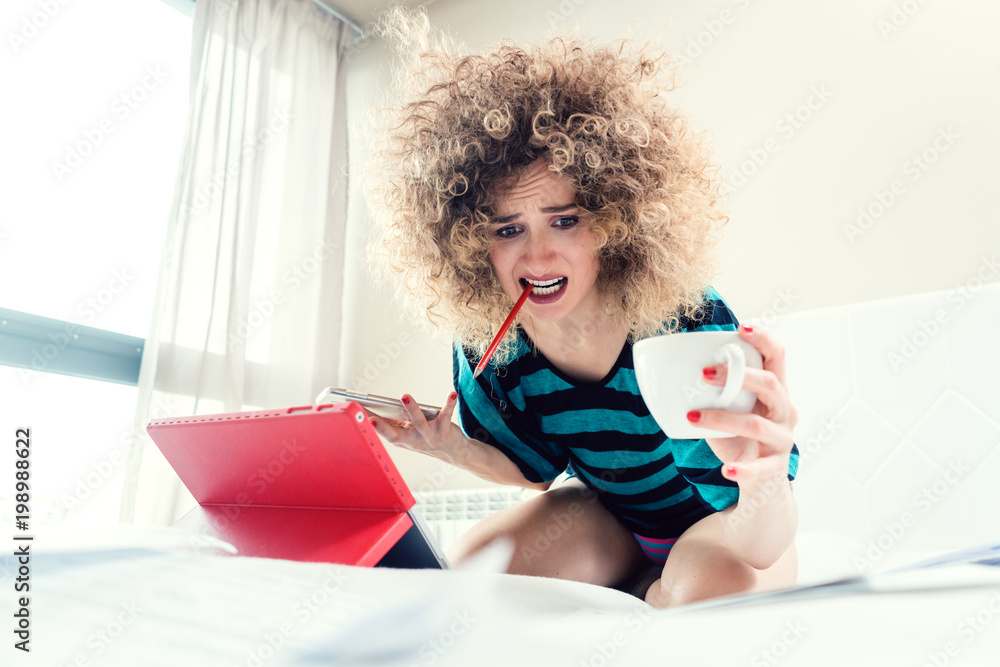Fotografie Woman student on her bed learning for exam in panic and despair