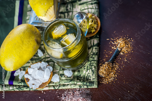 Close up of Indian and Asian famous mango juice AAM PANNA in a transparent glass with ice cubes and cumin powder ,sugar, and black salt in dark Gothic colors. photo