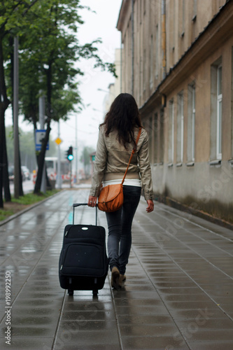 girl is traveling with a suitcase is walking along the street