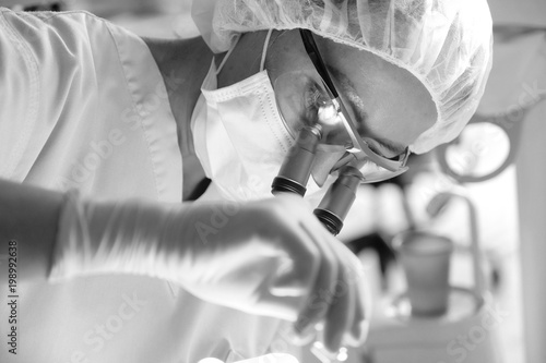 Female dentist in surgical uniform at the clinic in the treatment of a patient photo