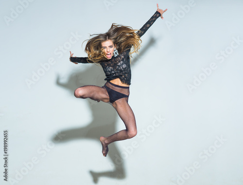 Fototapeta Naklejka Na Ścianę i Meble -  Lady on screaming face, enjoy freedom. Impudent lady looks attractive, sexy, light background. Girl in lace top and underwear, tights in black panties. Freedom concept. Sexy woman jump high in air.