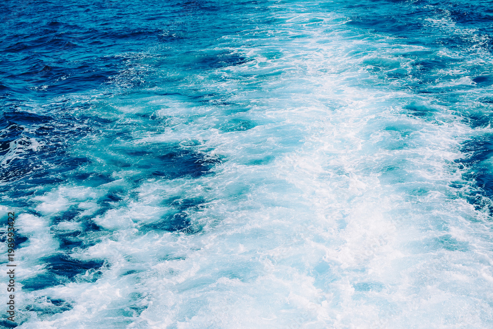 Obraz premium Waves, foam and wake in the ocean with blue water caused by cruise ship.