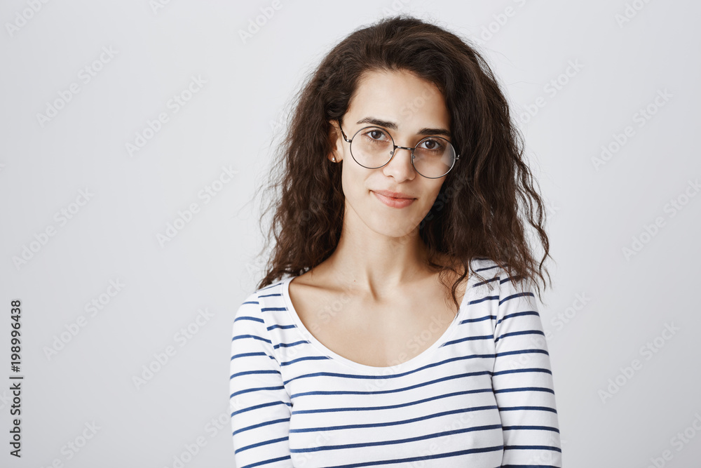 Waist-up shot of cute smart curly-haired girl in round glasses smiling broadly, being able to solve any riddle or issue, standing confident against gray background. Freelancer having break on coffee Waist-up shot of cute smart curly-haired girl in round glasses smiling broadly, being able to solve any riddle or issue, standing confident against gray background. Freelancer having break on coffee
