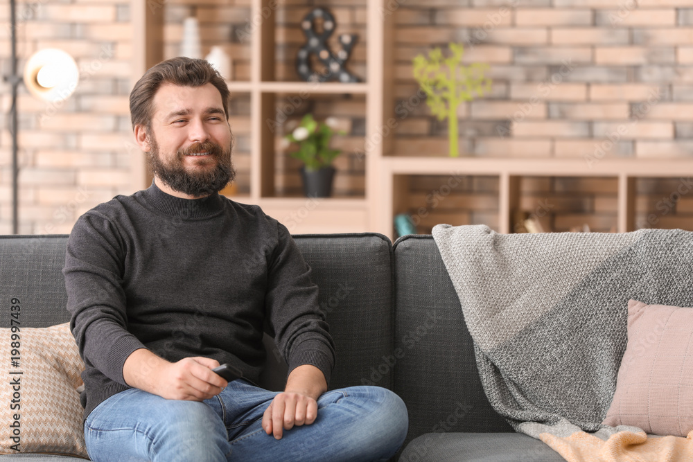 Man watching TV while resting on sofa at home