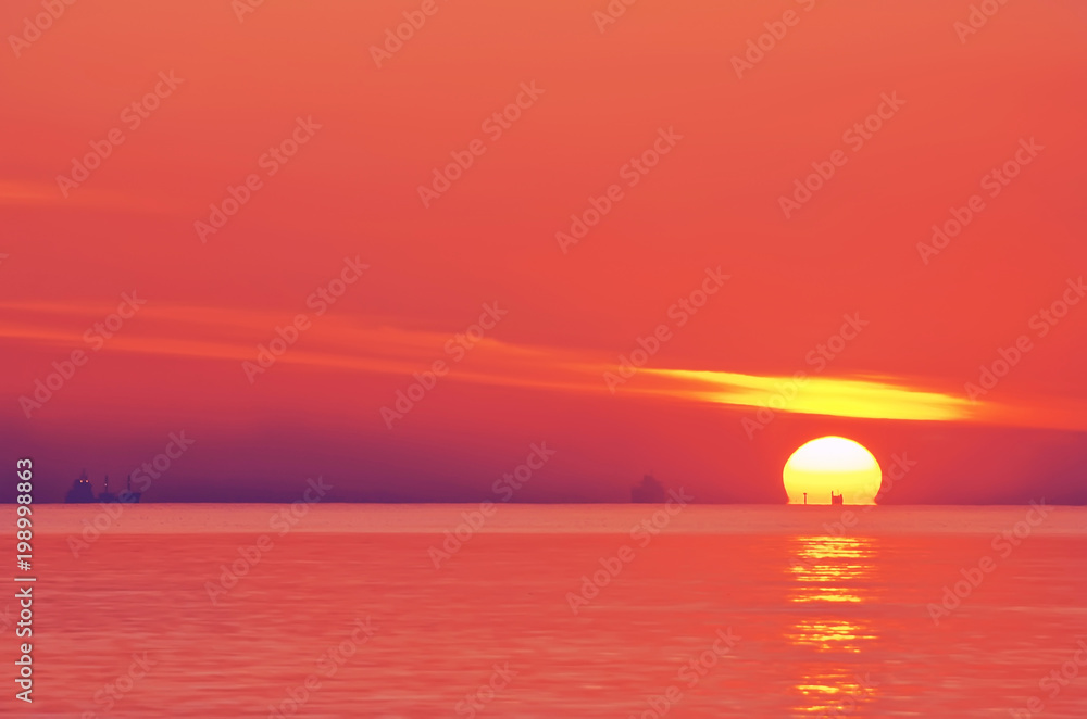 Red Dawn. A huge disk of sun rising from the sea surface and dark silhouettes of ships. Minimalism.

