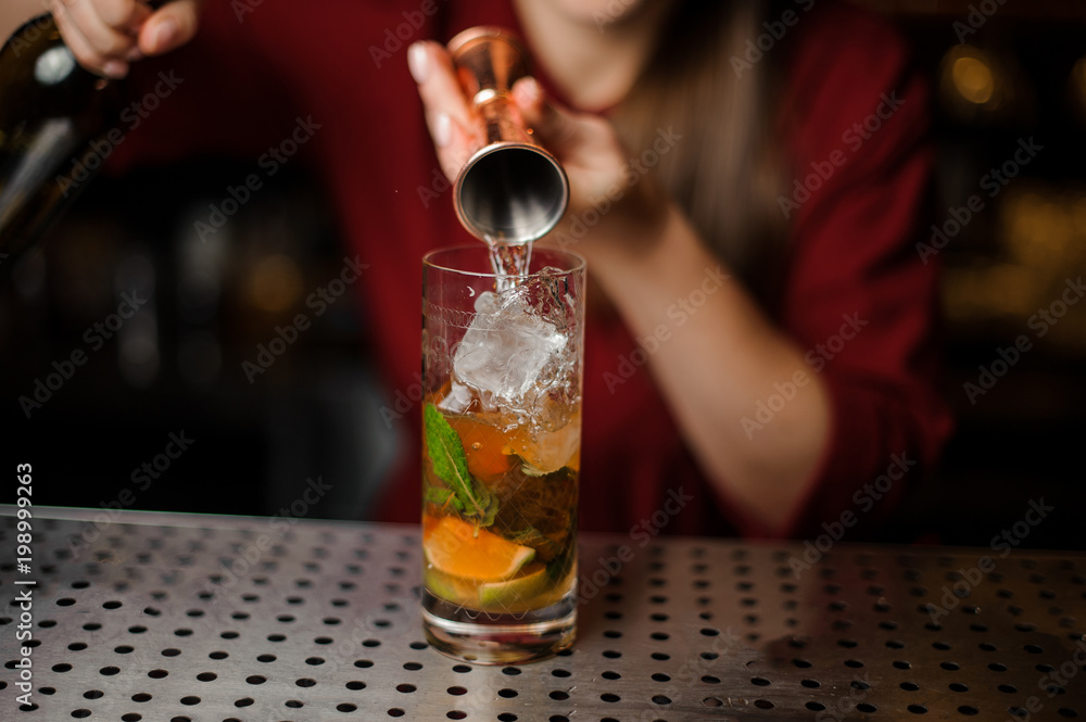 barmaid prepares a mojito in a crystal glass, adding white rum