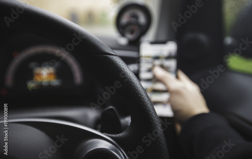 Driver on the phone whilst at the wheel of a car, texting and driving. 