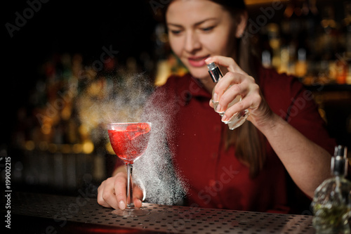 bartender girl adds peat whiskey to alcoholic cocktail