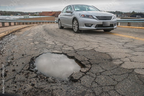 Foto Non descript car steering clear of big pothole