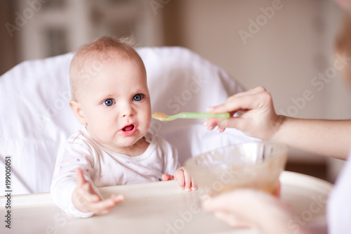 Mother feeding baby with mashed apple close up. Healthy nutrition. Childhood. Motherhood.