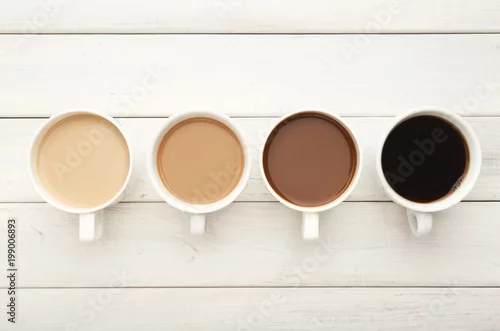 Obraz Różnorodne filiżanki na białym drewnie, odgórny widok