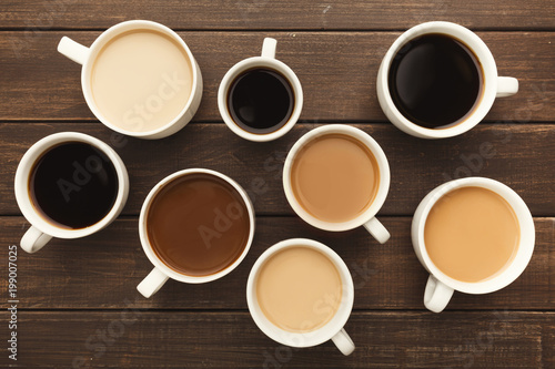 Different types of coffee in cups on wooden table, top view