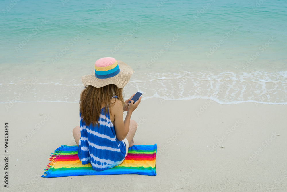 Young woman relaxing and using mobile phone at the tropical beach, Summer vacation and travel concept Young woman relaxing and using mobile phone at the tropical beach, Summer vacation and travel concept