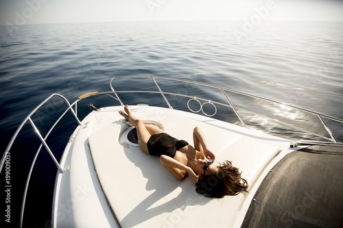 Young attractive woman poses on  luxury yacht floating on sea