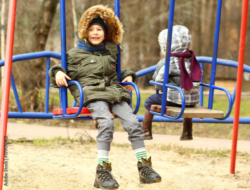 Happy boy swinging on the playground © Free_styler