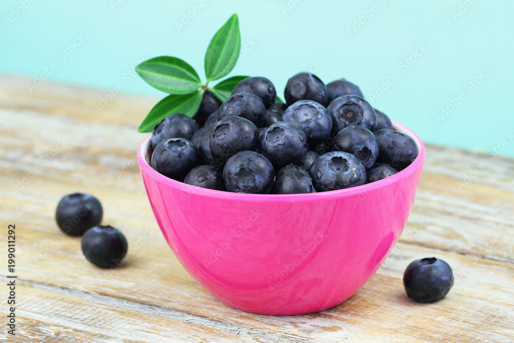 Fresh blueberries in pink bowl on wooden surface
Fresh blueberries in pink bowl on wooden surface