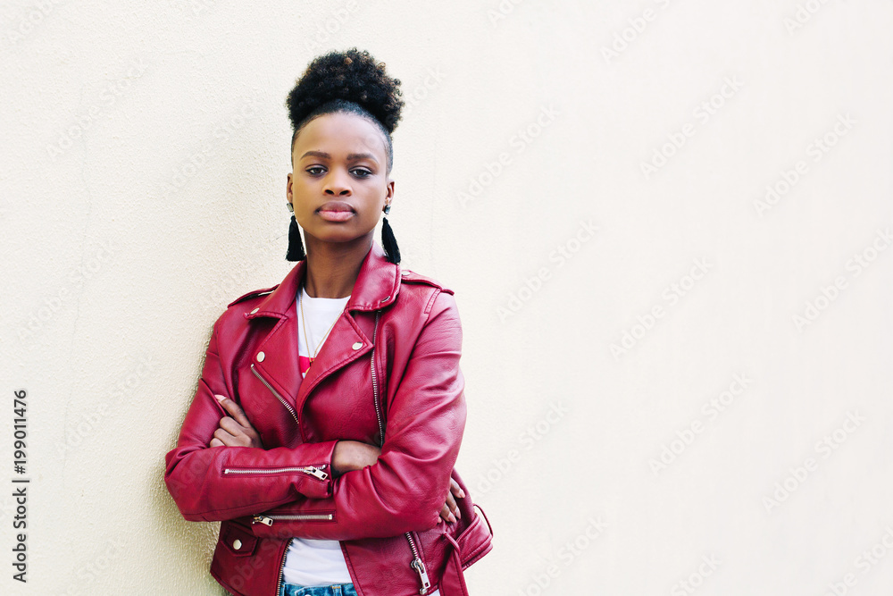portrait of cheerful black teenage girl with healthy looking skin and voluminous African hair dressed in red Leather Jacket on white background. Stock Photo Adobe Stock