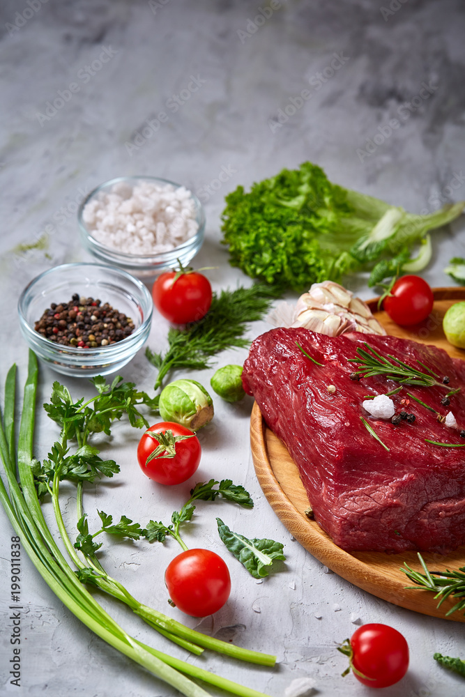 Still life of raw beef meat with vegetables on wooden plate over vintage background, top view, selective focus Still life of raw beef meat with vegetables on wooden plate over vintage background, top view, selective focus