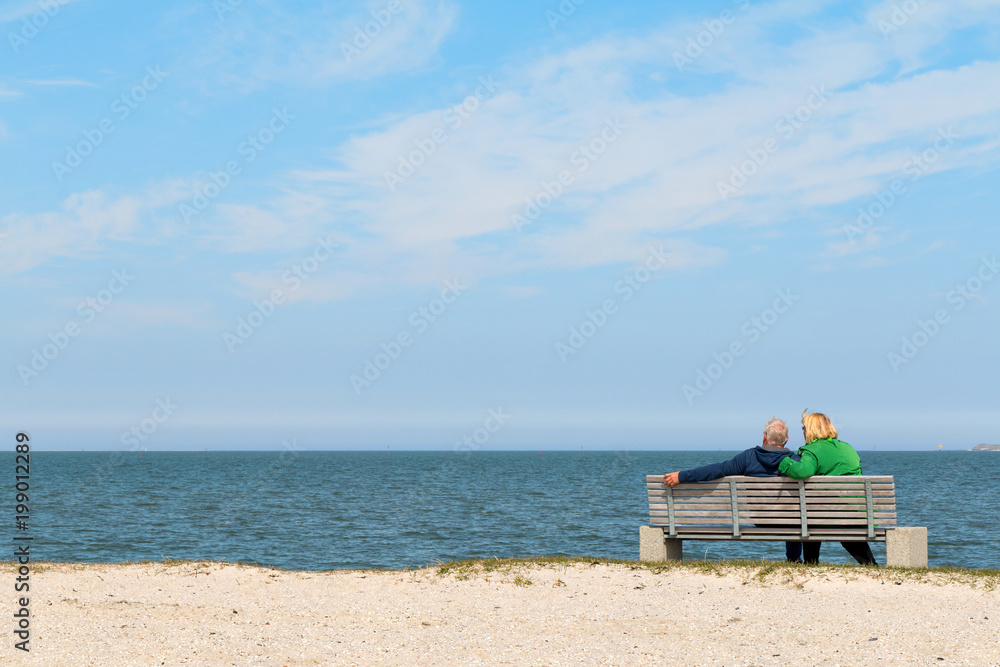 Couple sitting on bench and looking at the sea