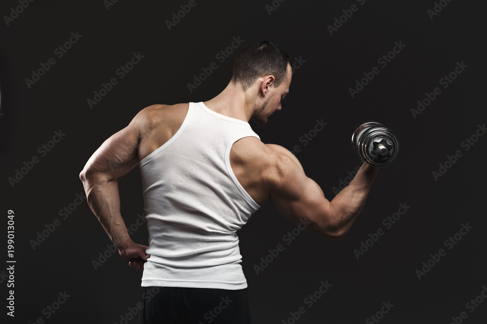 Strong athletic man with dumbbell showes muscular body