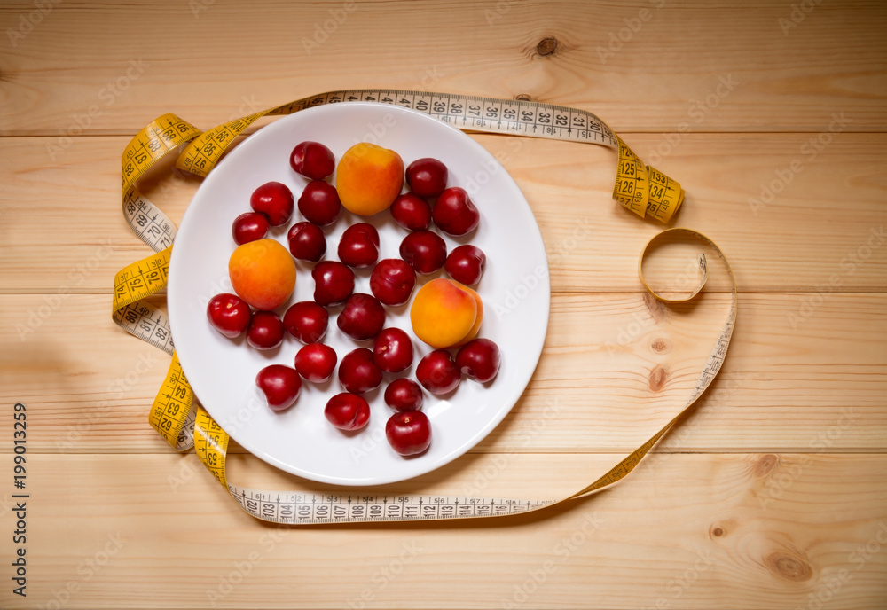 Fruits and measuring tape on wooden background. Top view. Weight loss and healthy diet. Fruits and measuring tape on wooden background. Top view. Weight loss and healthy diet.