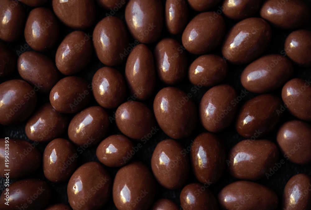 Chocolate candy textured background. Dark brown chocolate round candies on black concrete background top view, close up. Chocolate candy textured background. Dark brown chocolate round candies on black concrete background top view, close up.