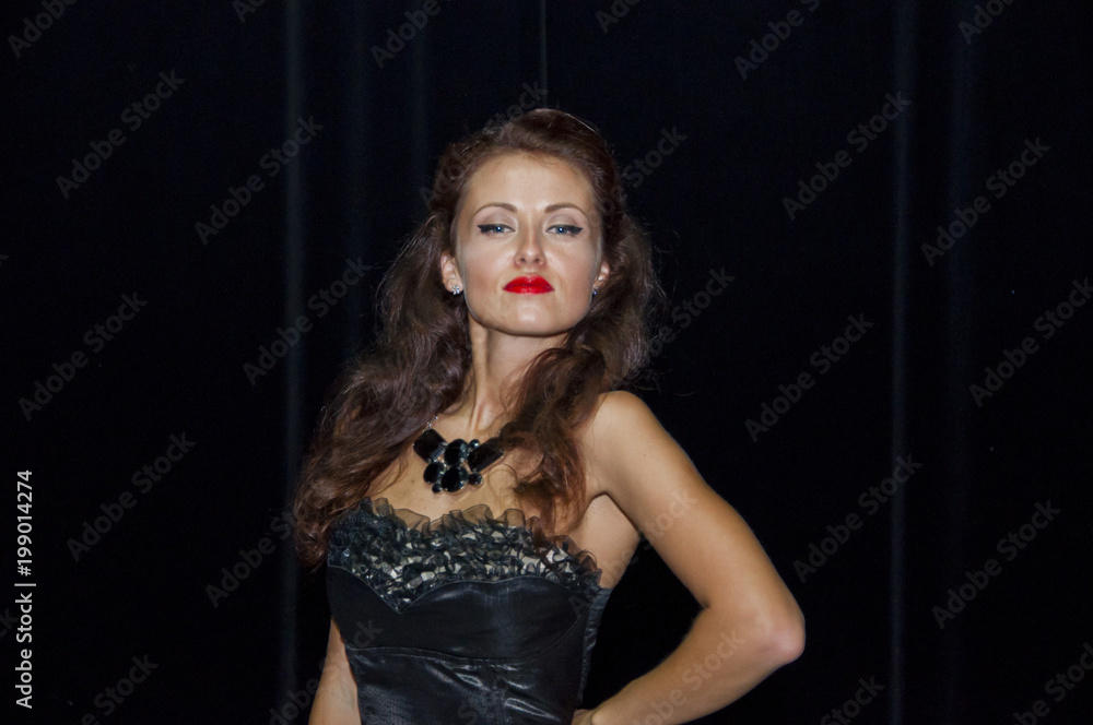Portrait of attractive sensual glamour retro elegant young adult smiling woman with classic hairstyle and red lips in evening dress indoor on black background Portrait of attractive sensual glamour retro elegant young adult smiling woman with classic hairstyle and red lips in evening dress indoor on black background